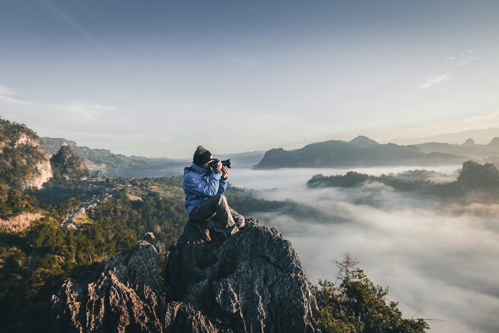 Homem no topo de uma montanha a tirar fotografias acima das nuvens